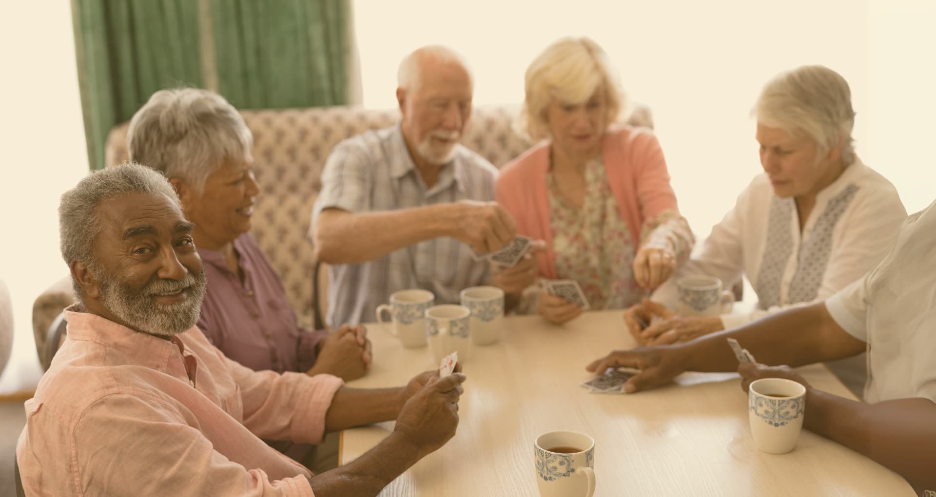 Residents playing cards together in a bright common room
